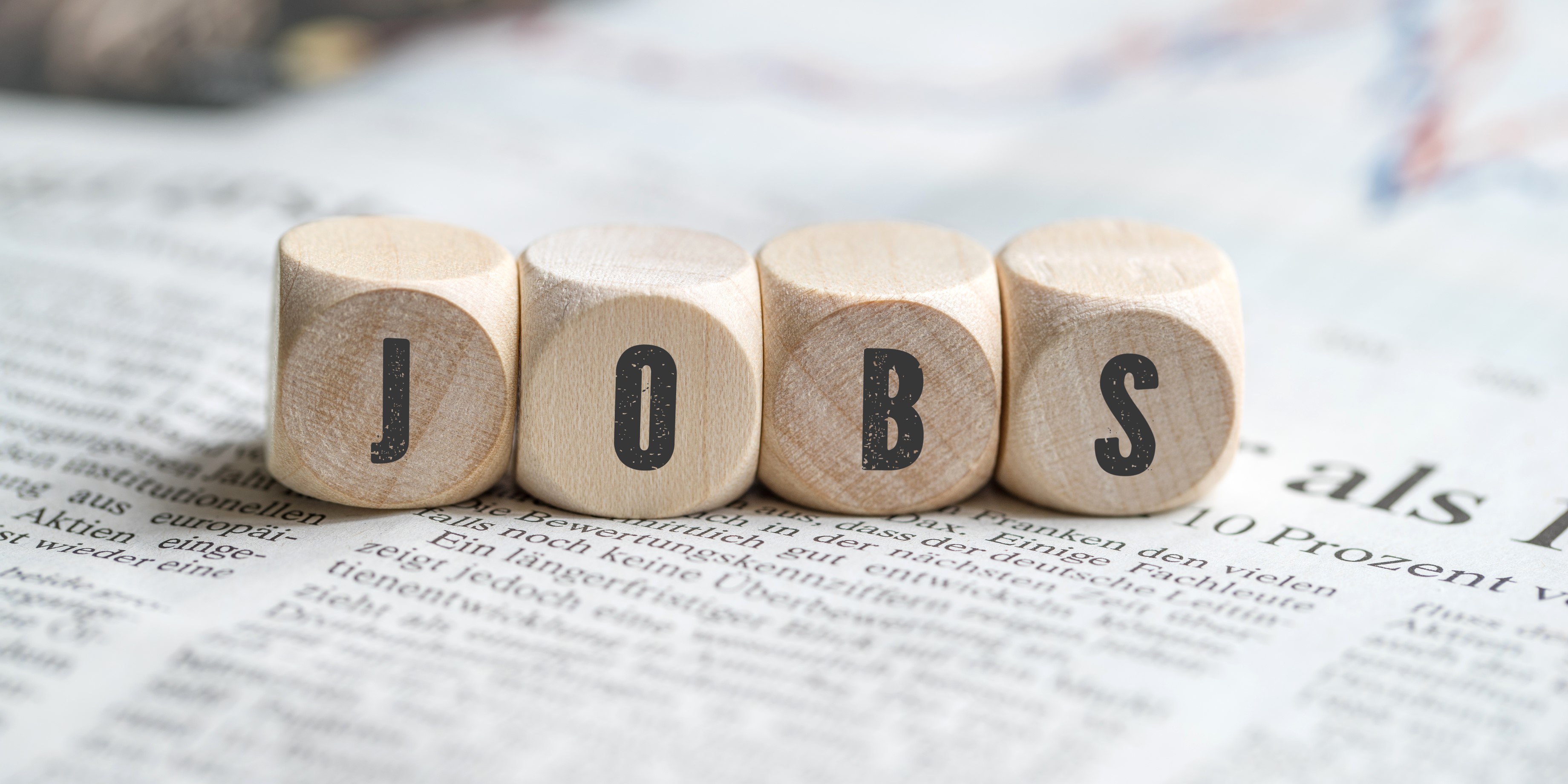 Vier Würfel die deren Beschriftung nebeneinander gelegt das Wort "Jobs" ergeben
